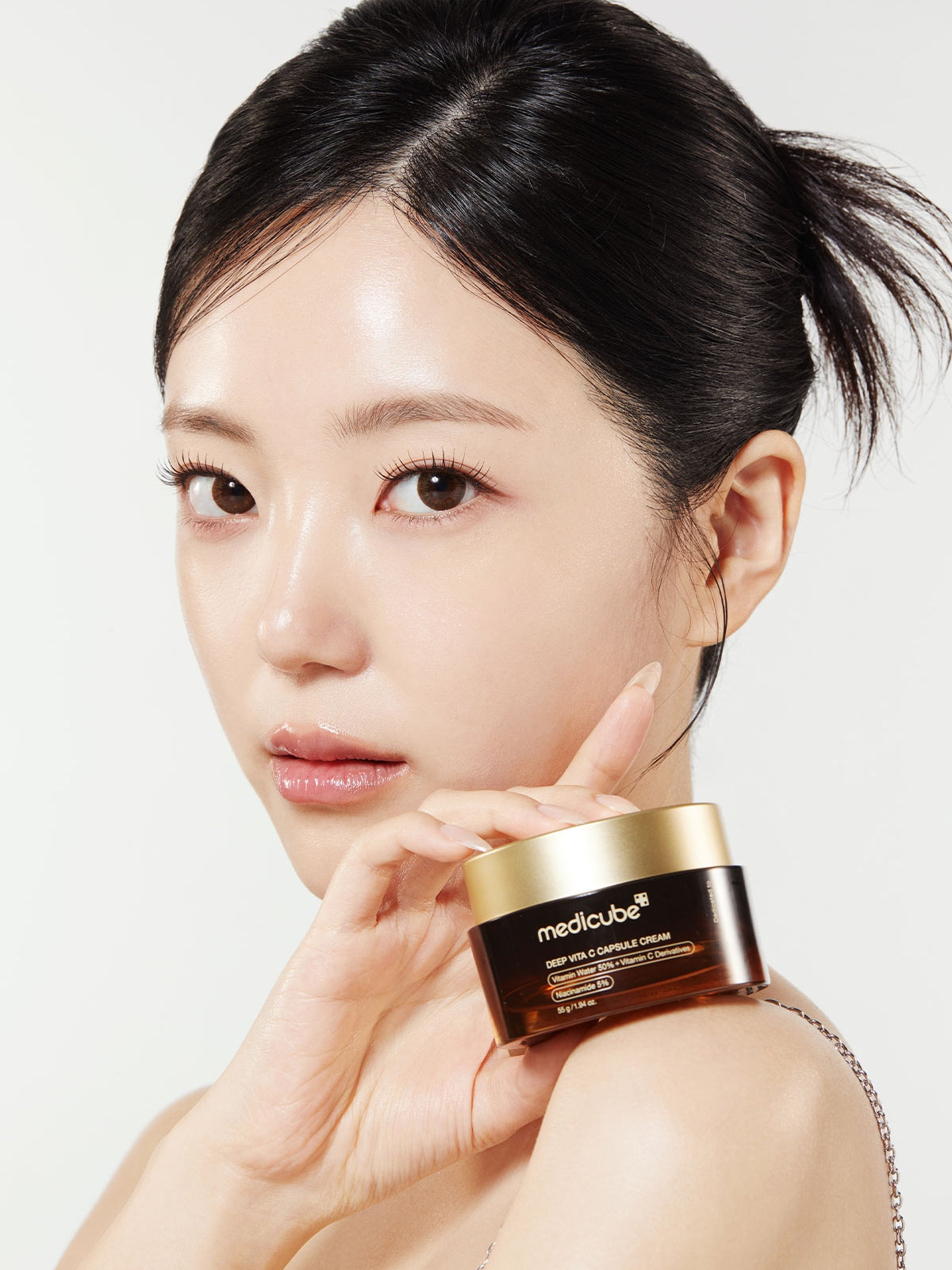 Woman holding a skincare product with a plain background