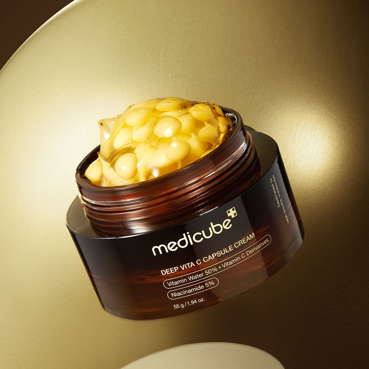 Medicube Deep Vita C Capsule Cream jar with cream visible on a gold background